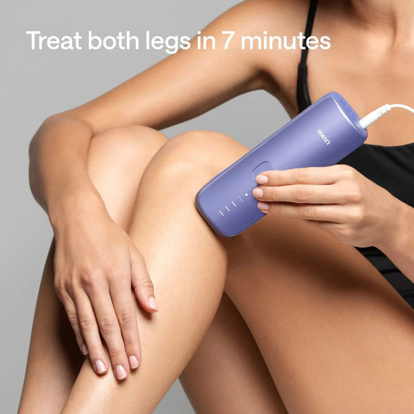 A woman using a purple leg hair removal device on her thigh, with text reading 'Treat both legs in 7 minutes' on a gray background.