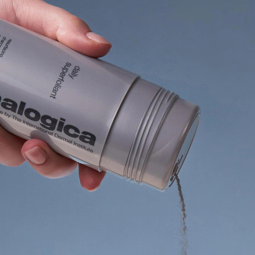 Hand holding a skincare product labeled 'alogica' against a blue background