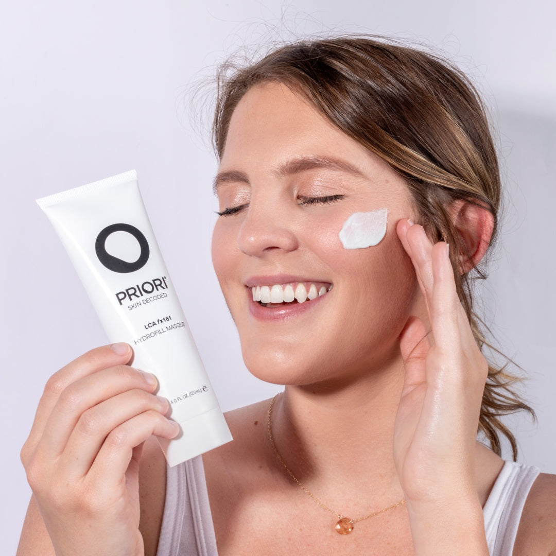 a woman holding a tube of PRIORI LCA - Hydrofill Mask