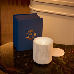 White candle with blue box on a marble surface