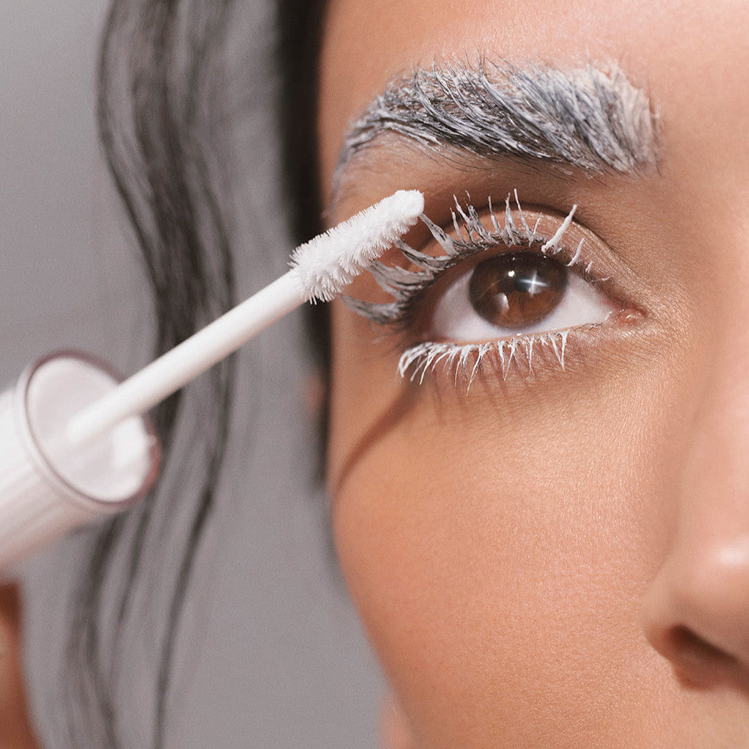 Person applying mascara with a brush to their eyelashes.