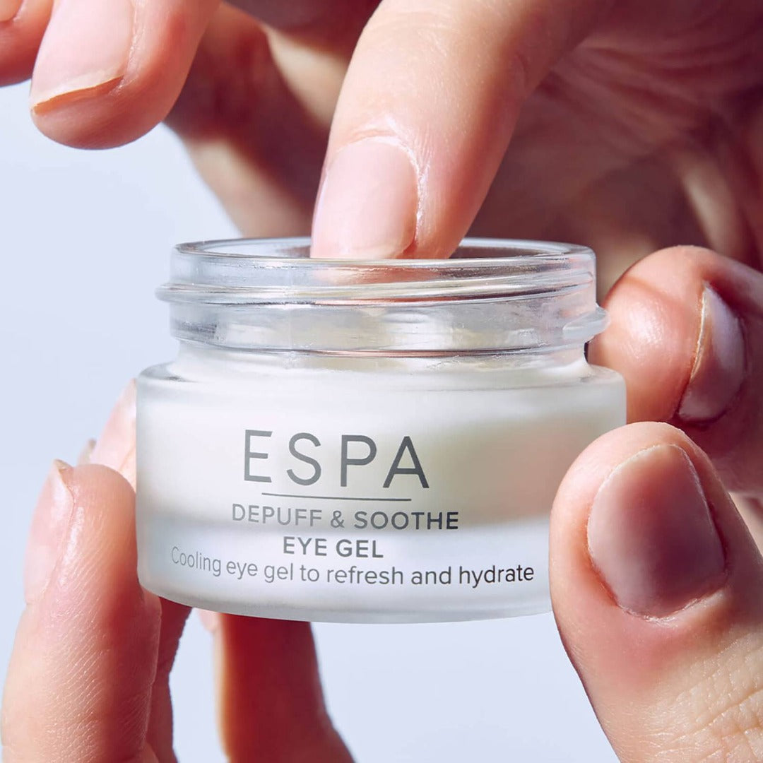 a hand holding a tub of ESPA Depuff & Soothe Eye Gel