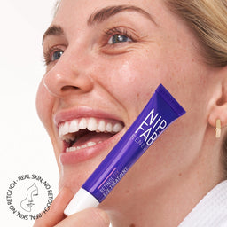 a model holding a tube of cream to her face