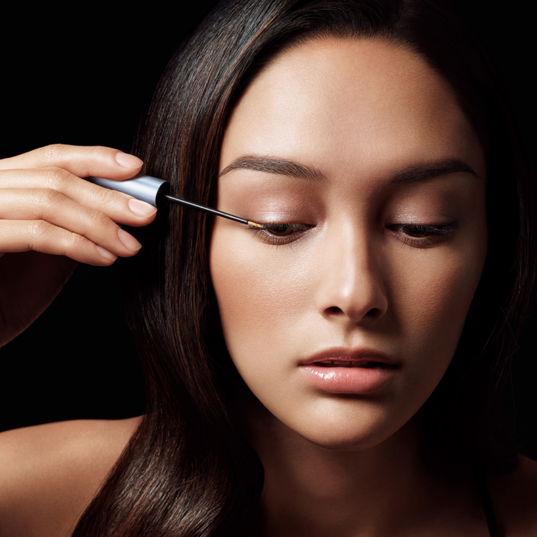 a closeup of a women applying the conditioner to her eyeklashes 