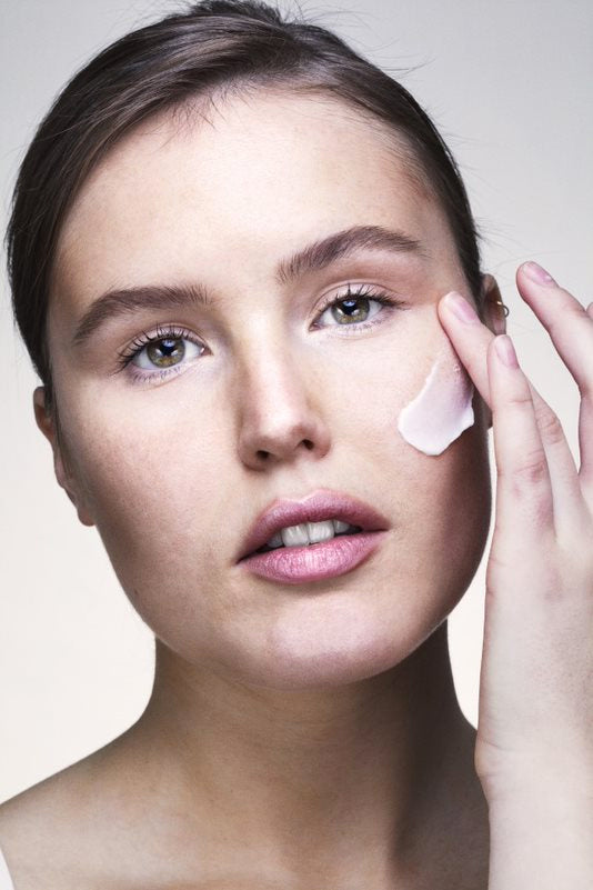 a woman applying cream to her face