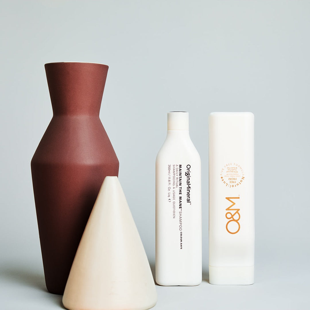 two O&M Maintain the Mane Conditioner bottles next to two ornaments 