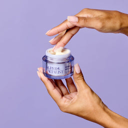 Hands scooping out day cream with one hand and holding the jar with the other hand